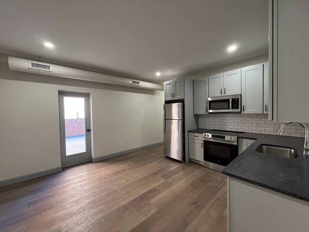 a kitchen with granite countertop a refrigerator and a stove top oven