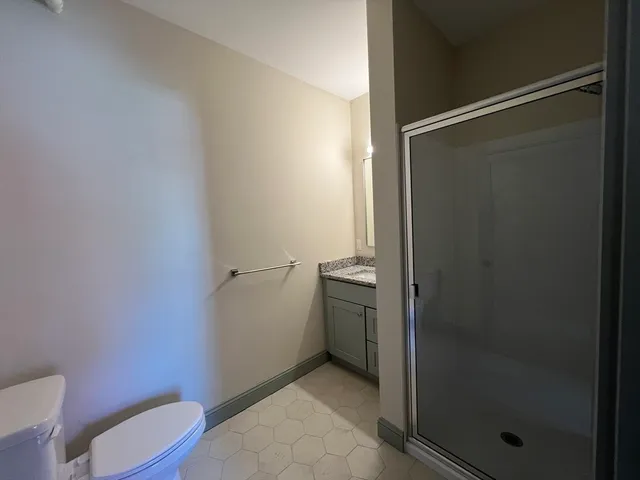 a bathroom with a granite countertop shower and a toilet