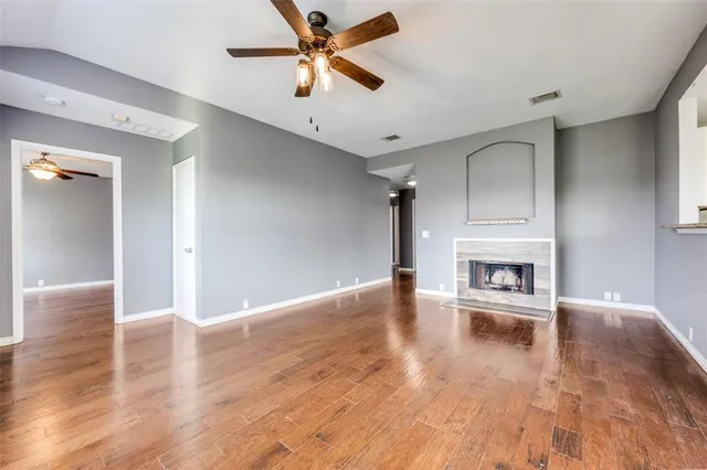 a view of a livingroom with wooden floor a ceiling fan and a kitchen