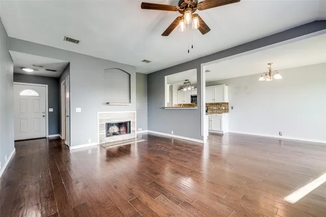 a view of a livingroom with wooden floor a ceiling fan and staircase
