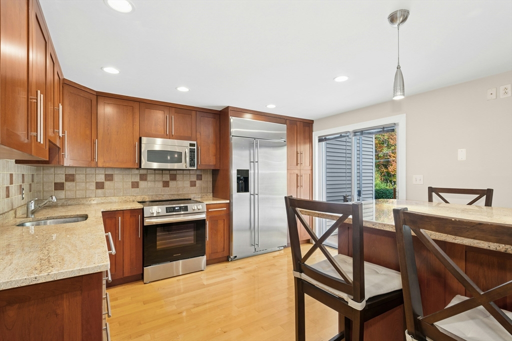 10 Erick Road, Unit 34 Mansfield, MA 02048 - Photo 6 of 24 a kitchen with stainless steel appliances granite countertop a stove top oven a sink dishwasher a dining table and chairs with wooden floor