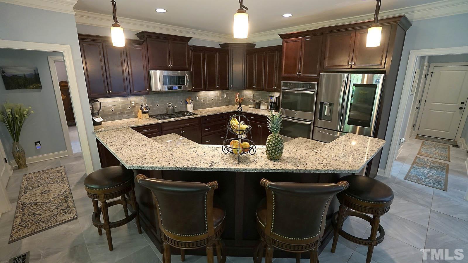 275 Hawfields Drive Pittsboro, NC 27312 - Photo 11 of 44 a kitchen with granite countertop a table chairs microwave and refrigerator