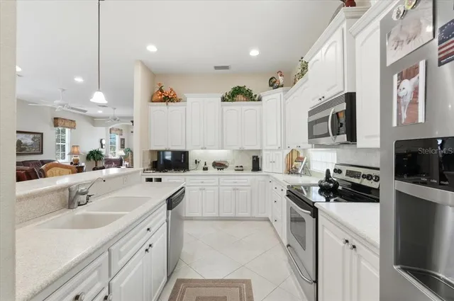 a kitchen with stainless steel appliances granite countertop a stove top oven a refrigerator a sink and a dining table with the kitchen view