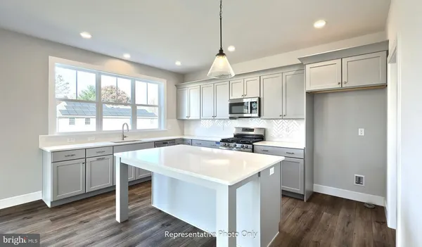 a kitchen with a sink a stove a refrigerator and white cabinets with wooden floor