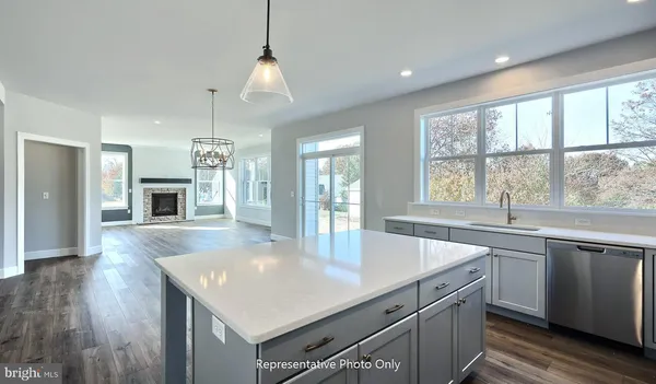 a kitchen with a stove center island a sink dishwasher and a fireplace with wooden floor