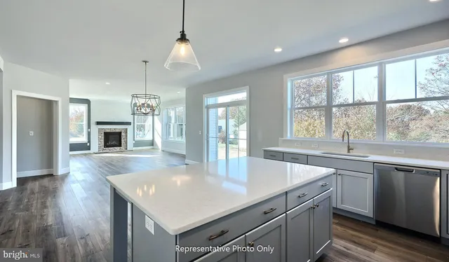 a kitchen with a stove center island a sink dishwasher and a fireplace with wooden floor