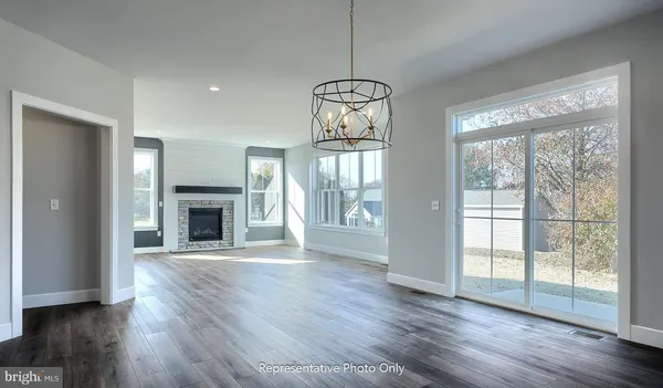 a view of an empty room with wooden floor fireplace and a window