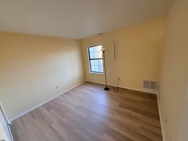 an empty room with wooden floor and window