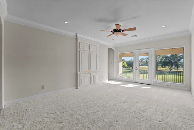 an empty room with windows and fan