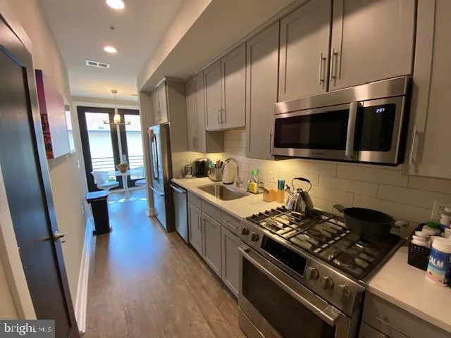 a kitchen with stainless steel appliances a stove a sink a microwave a refrigerator and cabinets