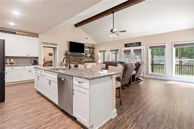 a kitchen with granite countertop a stove top oven a sink dishwasher a dining table and chairs with wooden floor