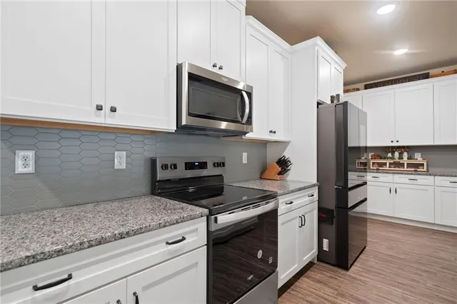 a kitchen with stainless steel appliances granite countertop white cabinets stove a sink and dishwasher