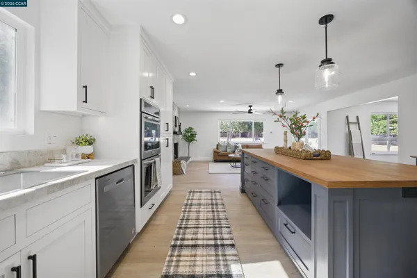a kitchen with granite countertop white cabinets and a wooden floor