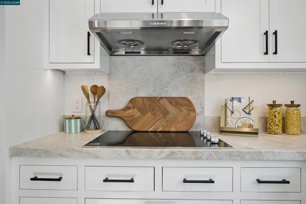 a kitchen with granite countertop white cabinets and a stove
