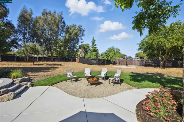 a view of a patio with a table and chairs under an umbrella with palm trees