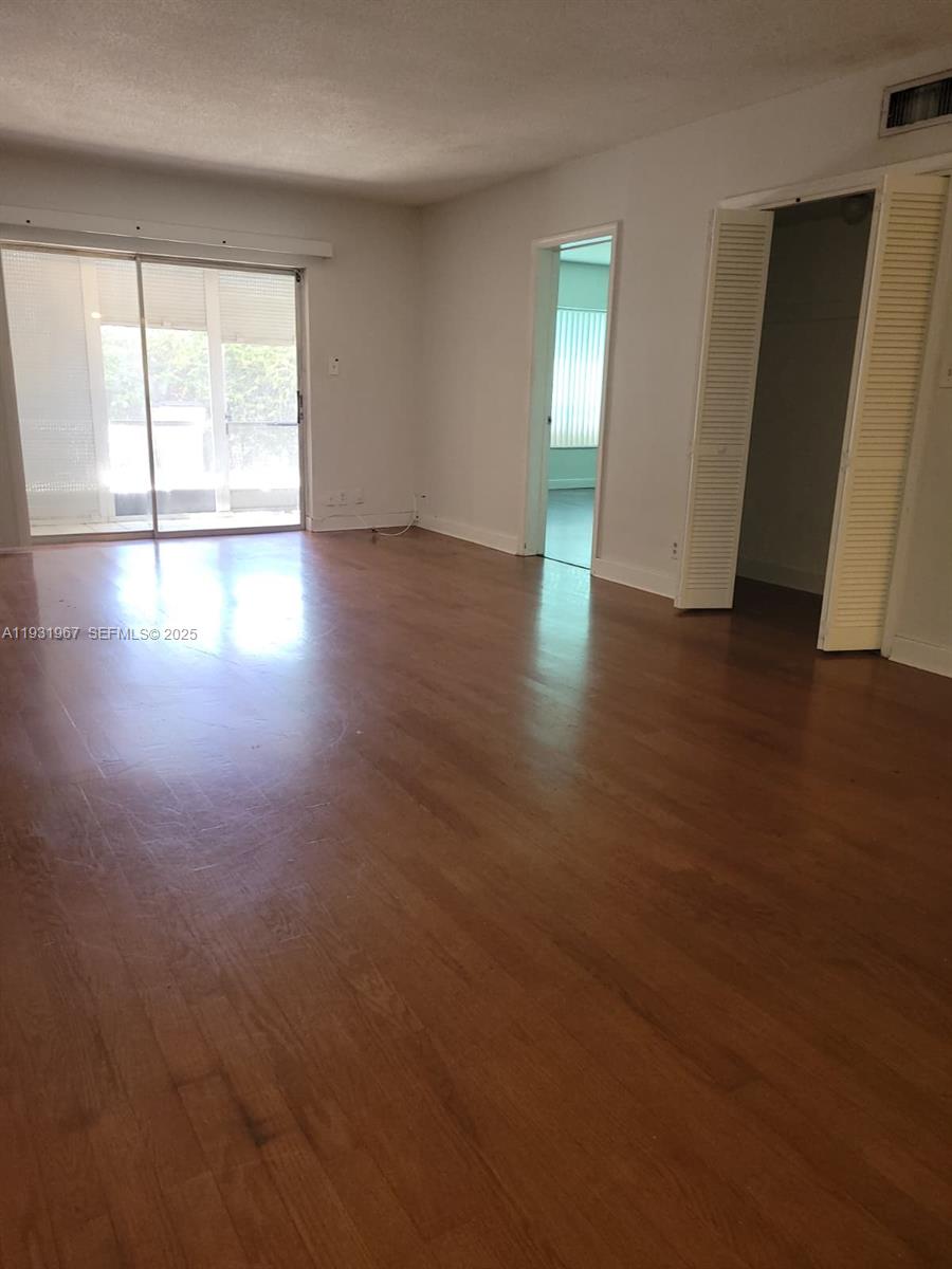 4321 Northwest 9th Avenue, Unit 102 Deerfield Beach, FL 33064 - Photo 14 of 34 an empty room with wooden floor and windows