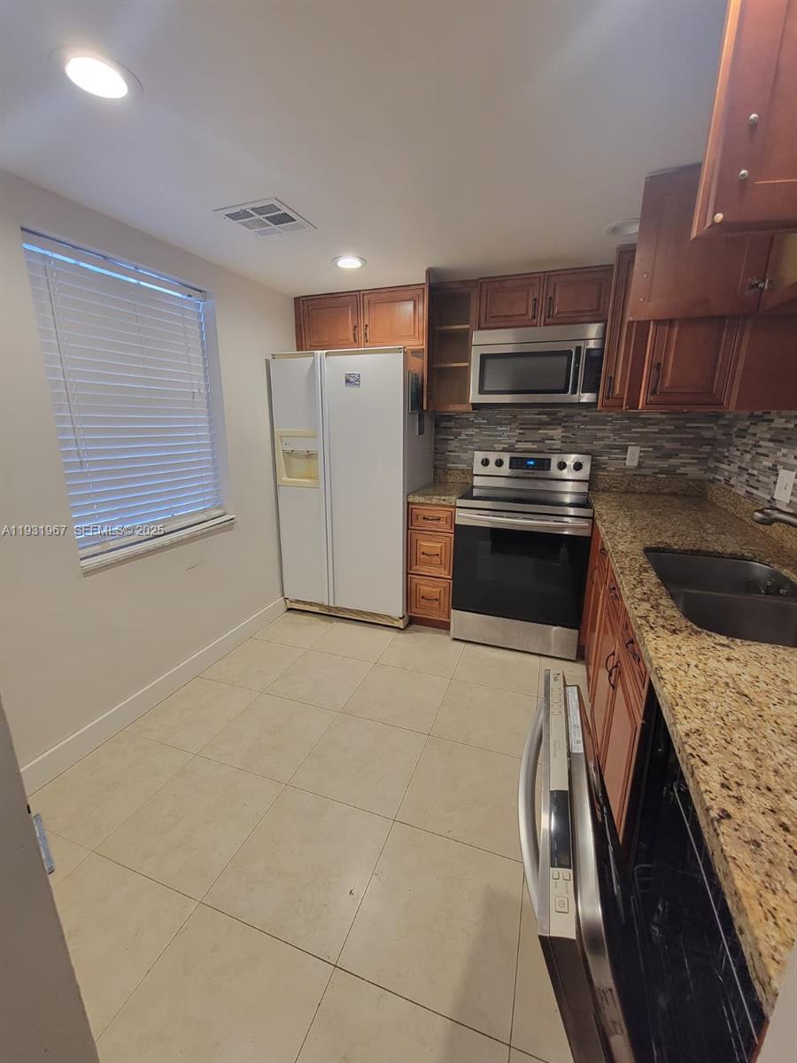4321 Northwest 9th Avenue, Unit 102 Deerfield Beach, FL 33064 - Photo 2 of 34 a kitchen with stainless steel appliances granite countertop a stove top oven a sink and a refrigerator