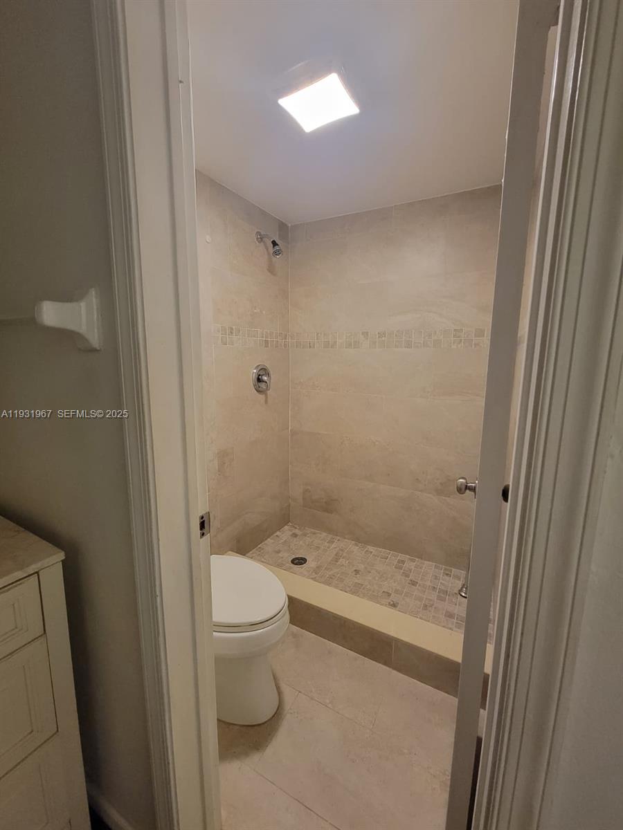 4321 Northwest 9th Avenue, Unit 102 Deerfield Beach, FL 33064 - Photo 24 of 34 a bathroom with a granite countertop toilet a sink and shower