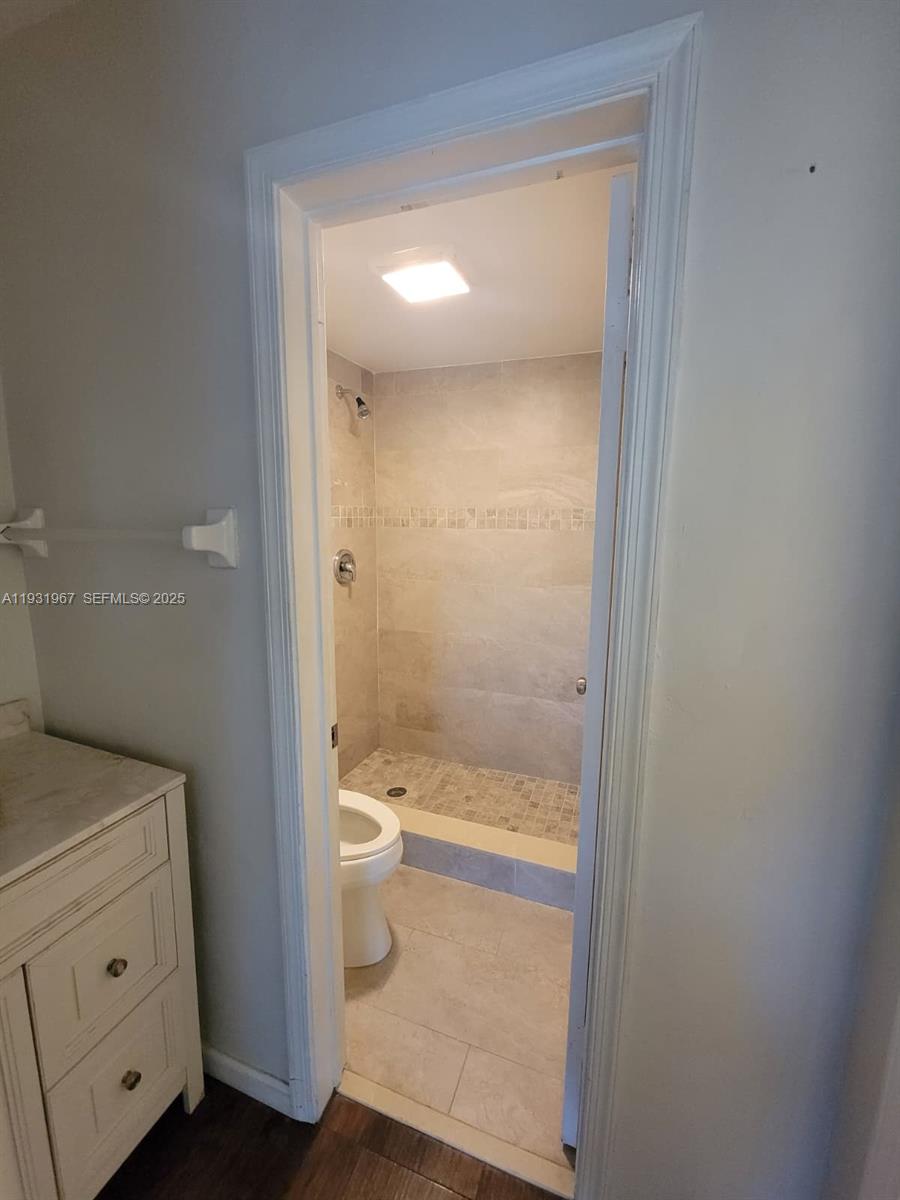4321 Northwest 9th Avenue, Unit 102 Deerfield Beach, FL 33064 - Photo 26 of 34 a bathroom with a granite countertop toilet a sink and shower