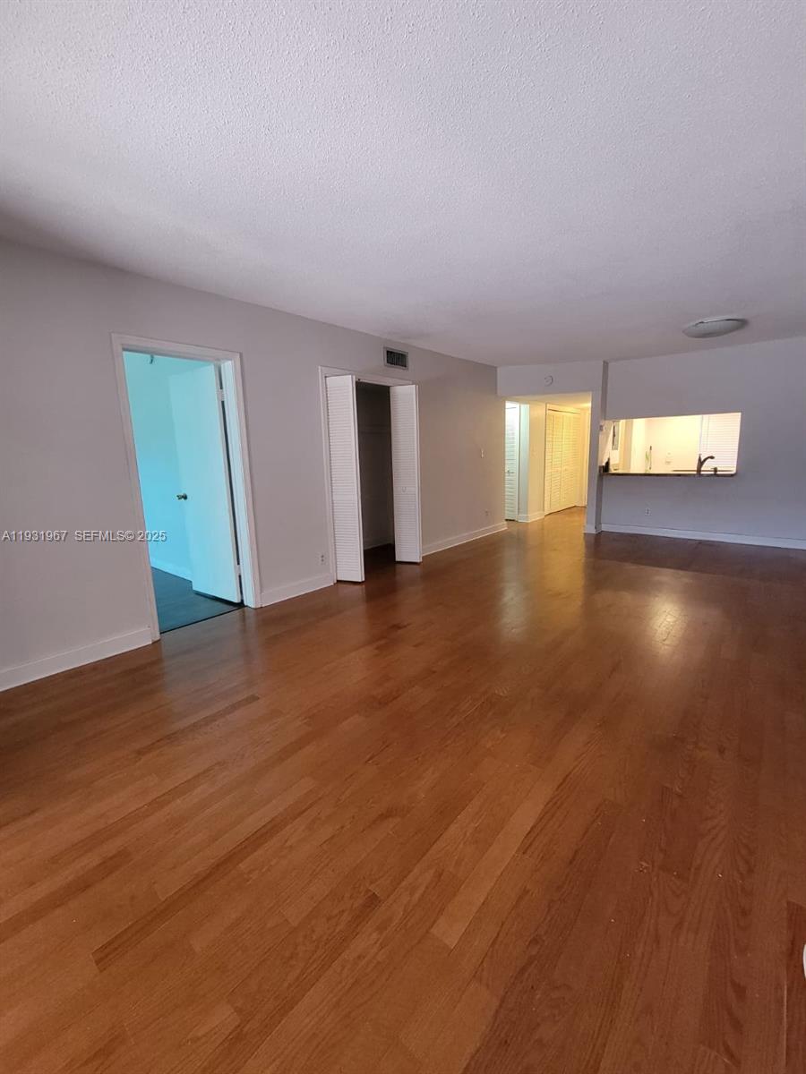 4321 Northwest 9th Avenue, Unit 102 Deerfield Beach, FL 33064 - Photo 9 of 34 an empty room with wooden floor and windows