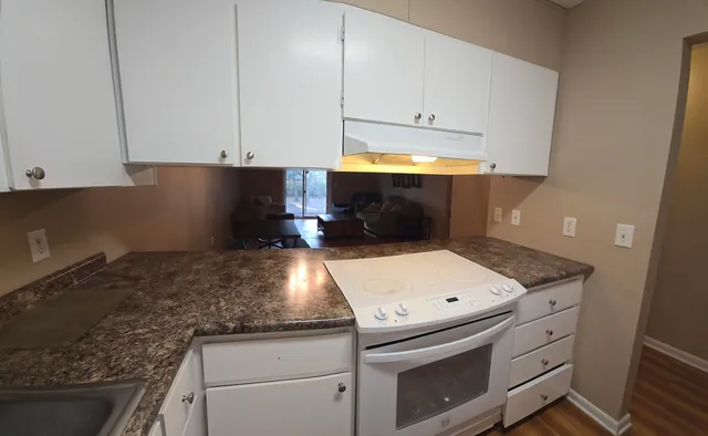a kitchen with granite countertop white cabinets and white appliances