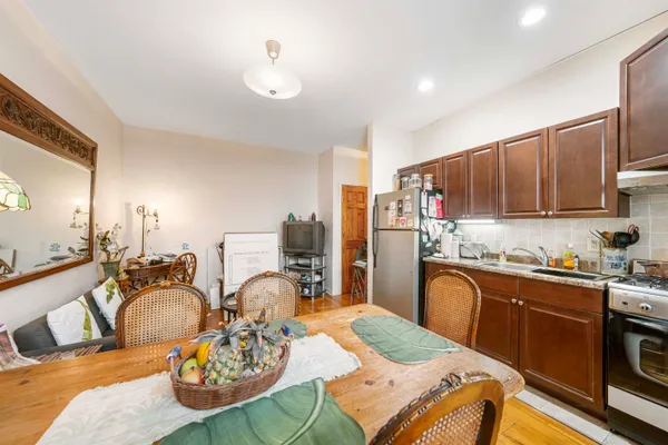 a kitchen with stainless steel appliances granite countertop a stove a sink dishwasher a dining table and chairs with wooden floor