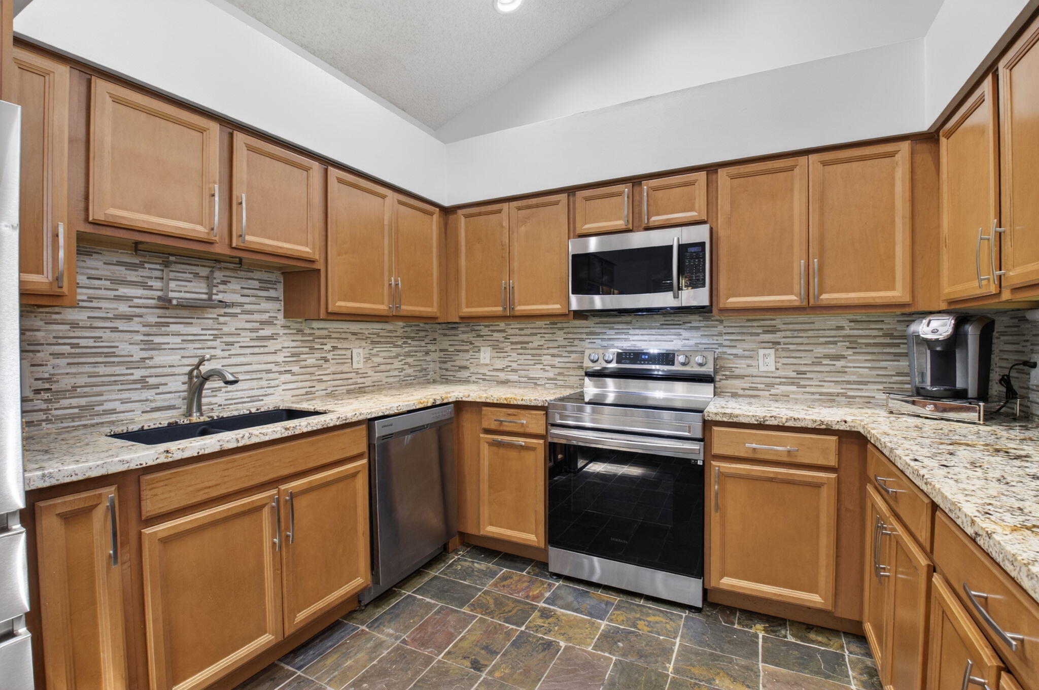 6694 Northwest 26th Way Boca Raton, FL 33496 - Photo 20 of 58 a kitchen with stainless steel appliances granite countertop a sink stove microwave and cabinets
