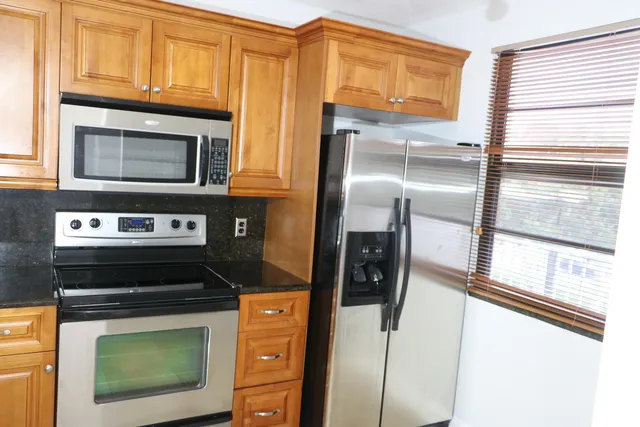 a kitchen with stainless steel appliances granite countertop a stove microwave and refrigerator