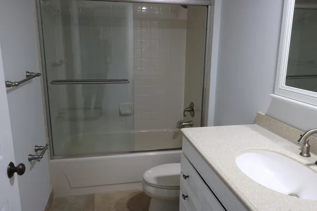 a bathroom with a granite countertop toilet a sink and a mirror