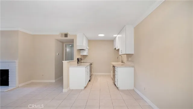 a kitchen with a sink a stove top oven and white cabinets