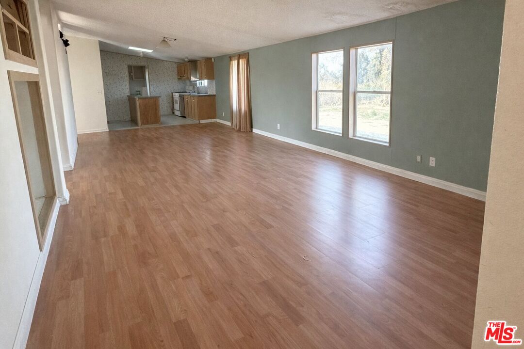 6288 Maricopa Road Phelan, CA 92371 - Photo 9 of 17 an empty room with wooden floor and windows