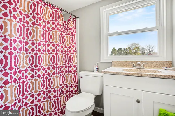 a bathroom with a granite countertop sink mirror vanity and toilet