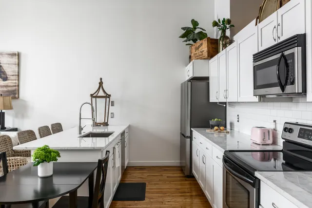 a kitchen with stainless steel appliances a sink a stove a microwave a dining table and chairs