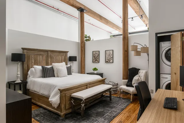 a bedroom with a bed wooden floor and a large window