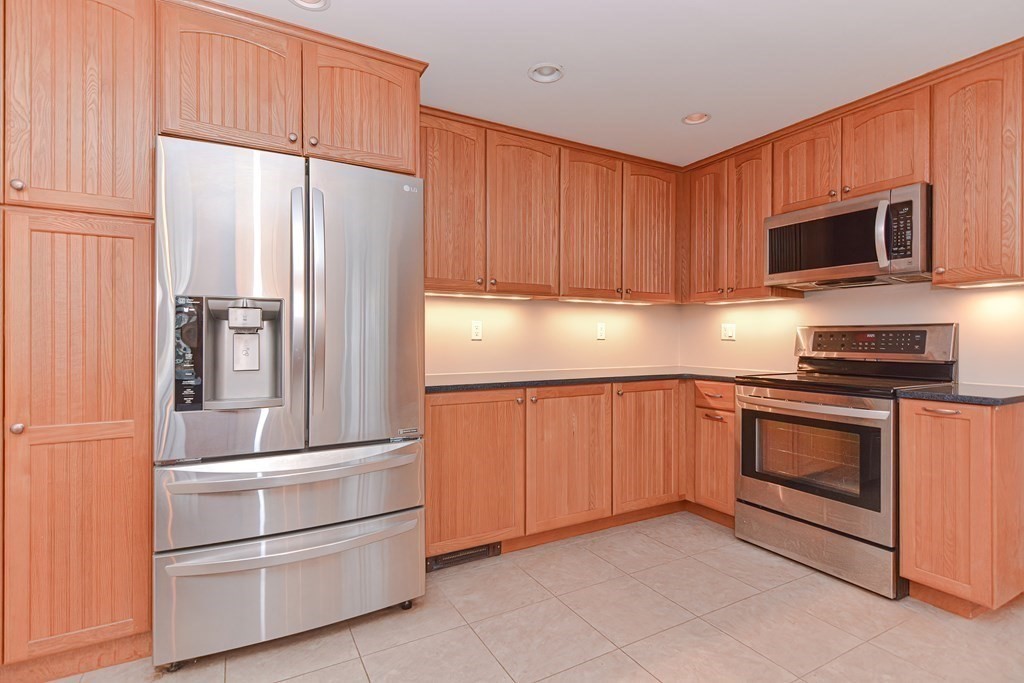 4 Bugli Lane Wakefield, MA 01880 - Photo 6 of 32 a kitchen with granite countertop white cabinets and stainless steel appliances