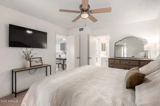 a bedroom with a bed a flat screen tv and a chandelier