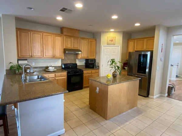 a kitchen with stainless steel appliances granite countertop a refrigerator a sink a stove top oven and a refrigerator