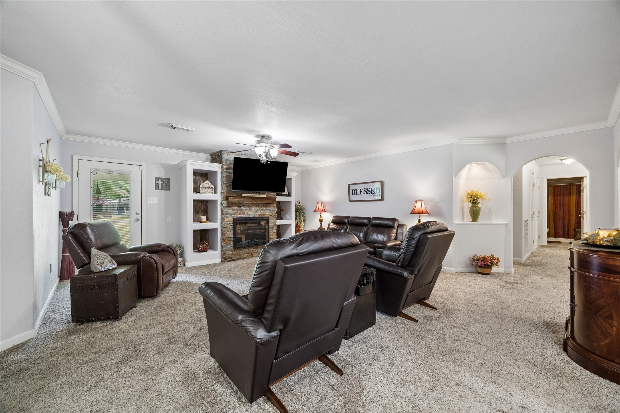 Living room featuring a fireplace, a lit recessed art niche, and access to the back door