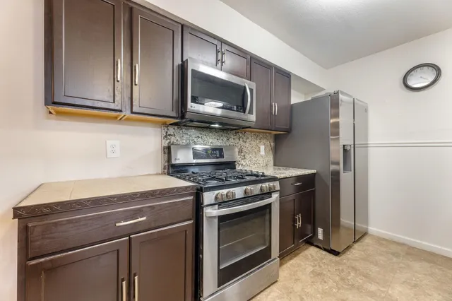 a kitchen with stainless steel appliances granite countertop a stove microwave and refrigerator