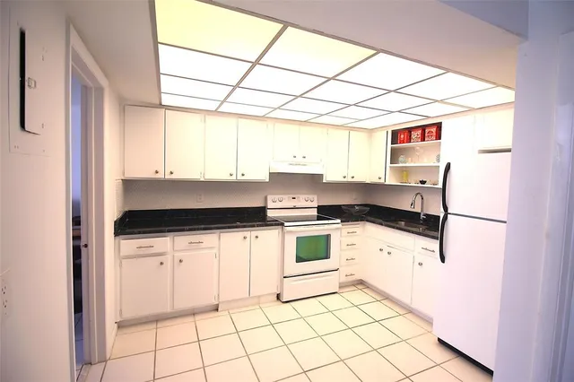 a kitchen with granite countertop white cabinets and white appliances