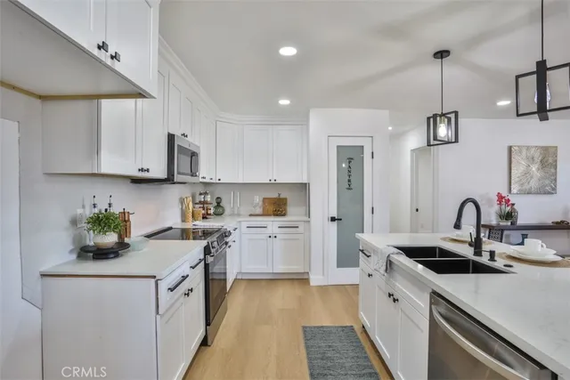 a kitchen with a sink dishwasher a stove a microwave oven and a dining table with wooden floor