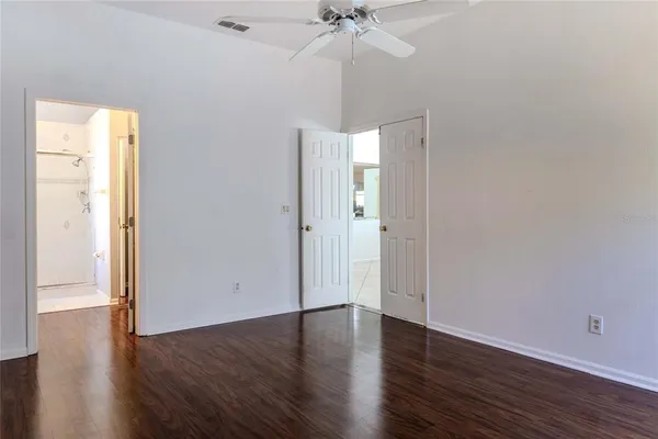 an empty room with wooden floor and a ceiling fan