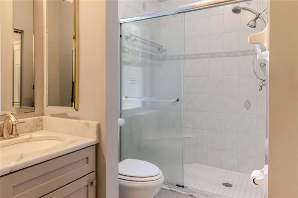 a bathroom with a granite countertop shower a sink and toilet