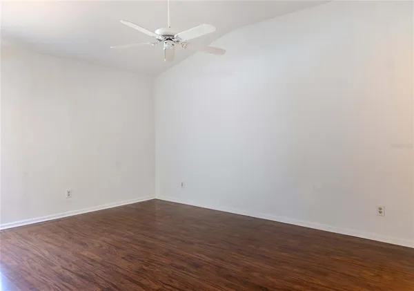 an empty room with wooden floor and fan