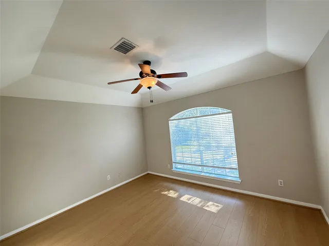an empty room with windows and fan