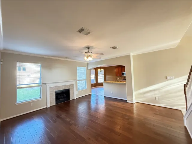 an empty room with wooden floor fireplace and windows