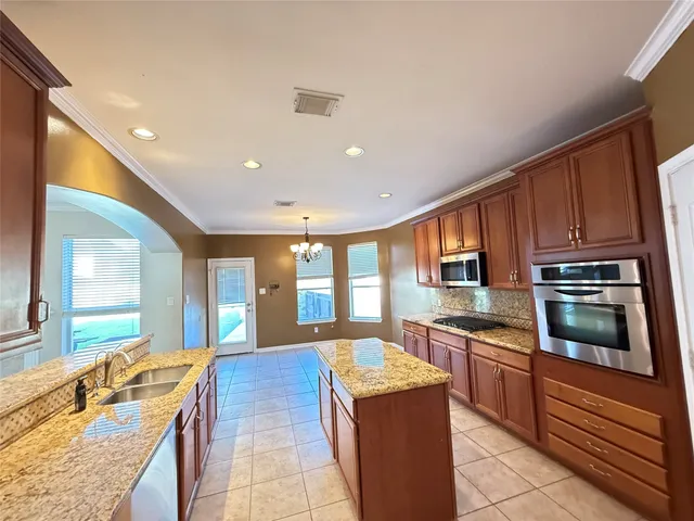 a large kitchen with stainless steel appliances granite countertop a stove and a sink