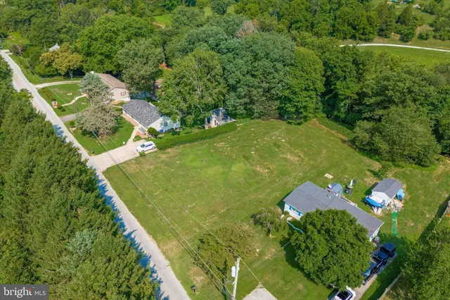 an aerial view of a residential houses with outdoor space and trees all around