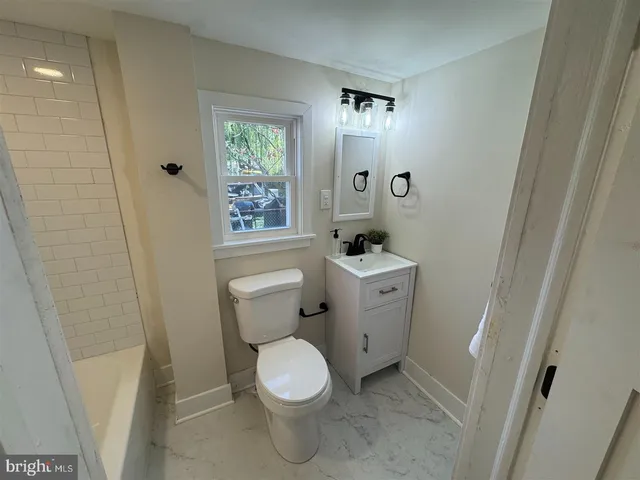 a white toilet sitting next to a bathroom sink and a window