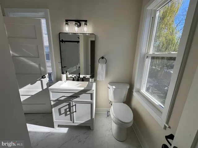 a bathroom with a granite countertop sink toilet and mirror